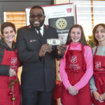 Sarah Woodrum, Sheldon Greenland, Evelyn Sullivan and Claire Von Boetticher pose for a photo with the $1,000 bill donation at Hobby Lobby on Saturday.